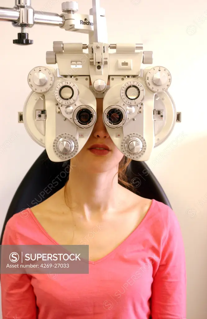 Ophthalmology. Woman looking through a refractor during an eye examination at an ophthalmologist. This equipment measures and corrects refractive errors of the eye. It helps ophthalmologist in choosing lenses to correct the sight of a patient.