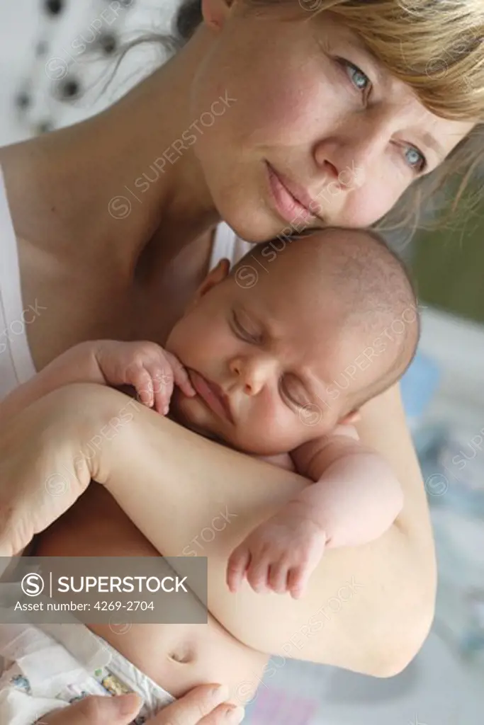 2 months old baby sleeping in the arms of her mother.