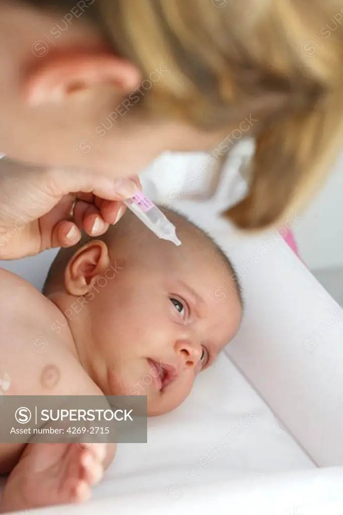 Mother putting eye-drops in her 2 months old baby's eyes.