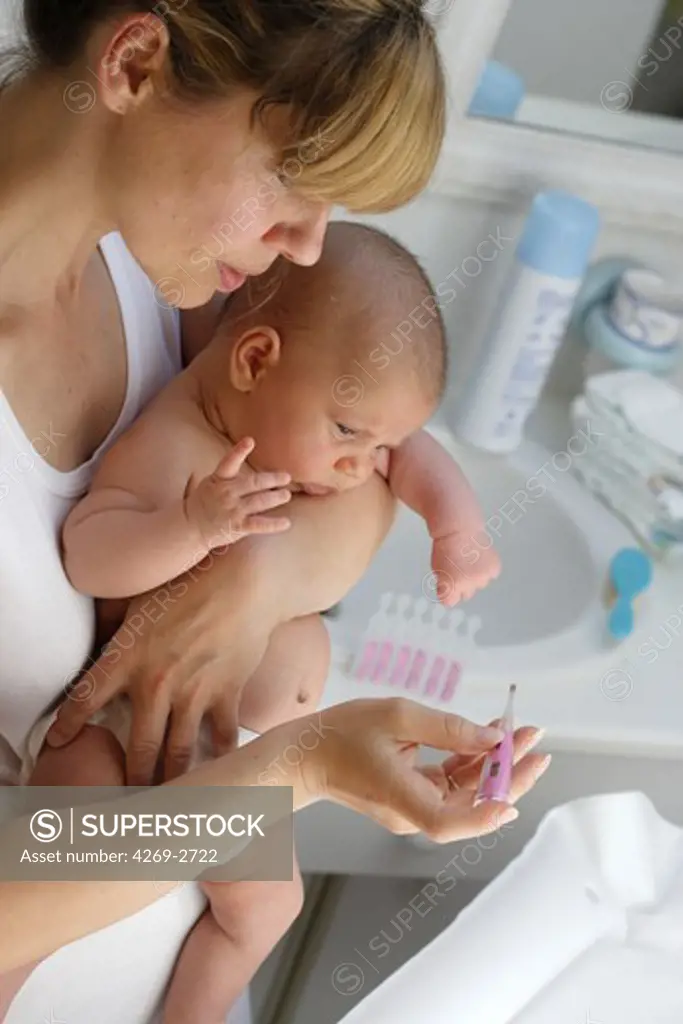Mother checking the temperature of her 2 months old feverish baby with a digital thermometer.