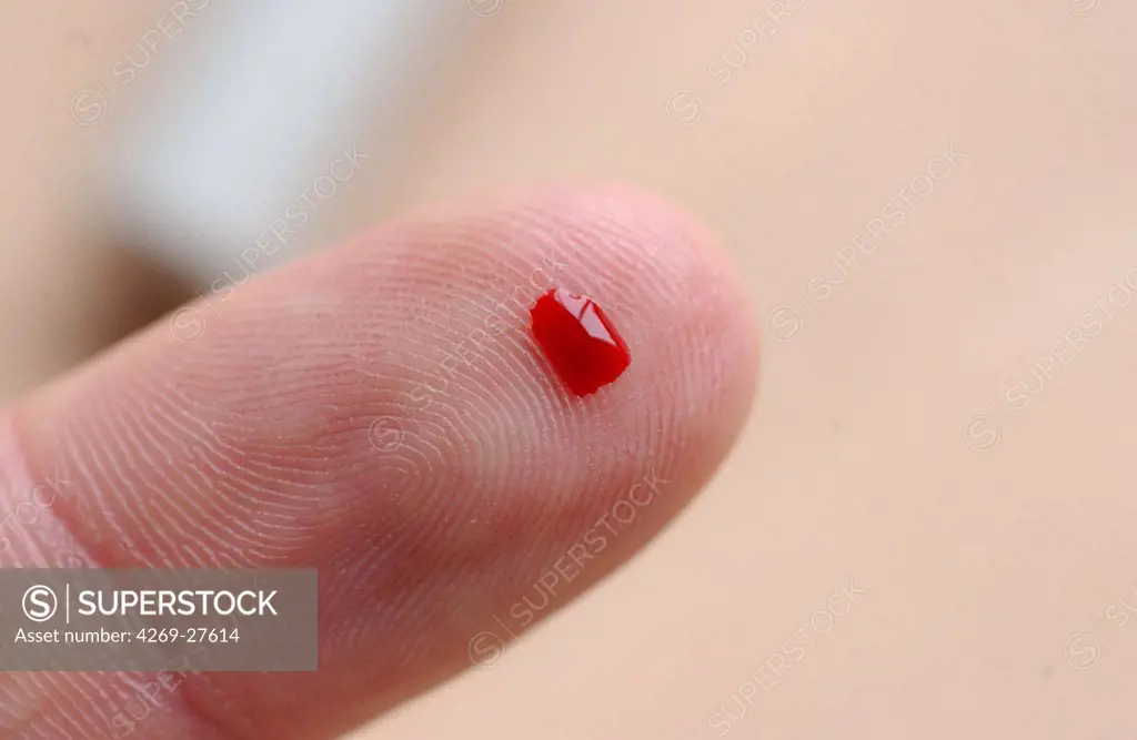 Diabetes. Drop of blood : a diabetic person is checking her blood sugar level (self glycemia). A drop of blood obtained with a pen-like lancing device is placed on a test stick and analysed with blood glucose tester (glucometer).