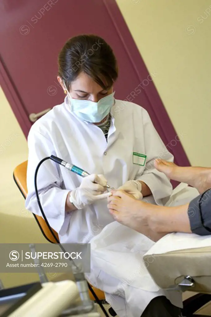 Pedicure-chiropodist performing confort care on a patient's foot (removing of hardened and calloused skin).