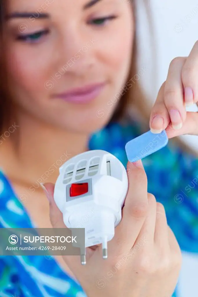 Woman using an electric mosquito diffuser