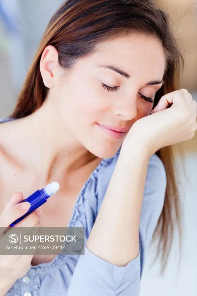 Woman applying essential oils on her wrist with a roll-on.