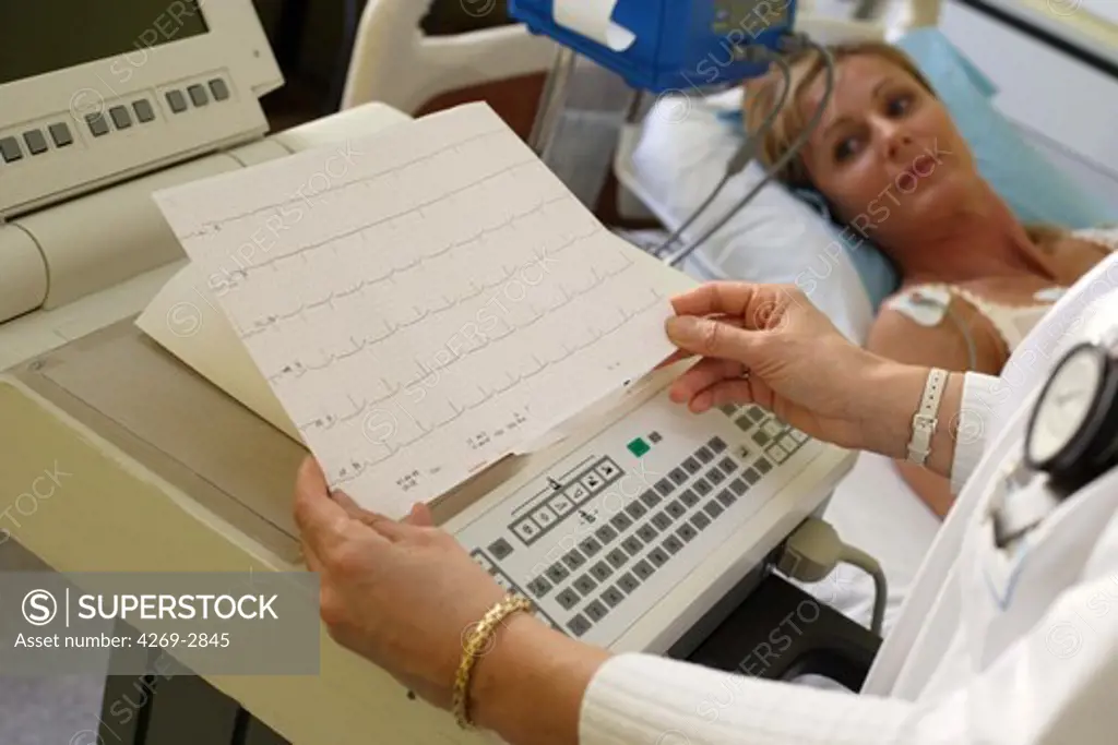 38 years old female patient undergoing an electrocardiography (EKG) examination. Electrodes attached to her chest measure the electrical activity of her heart. The results are recorded by the EKG machine as an electrocardiogram.