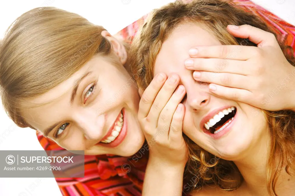 Woman covering her girlfriend's eyes with hands.