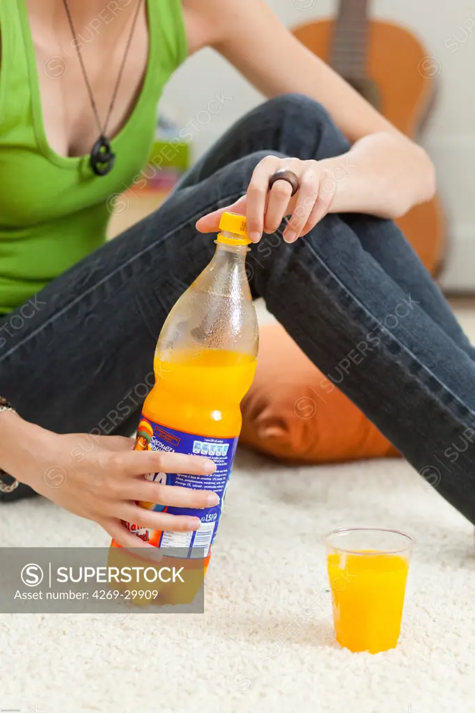 Teenage girl pouring a glass of orange juice.