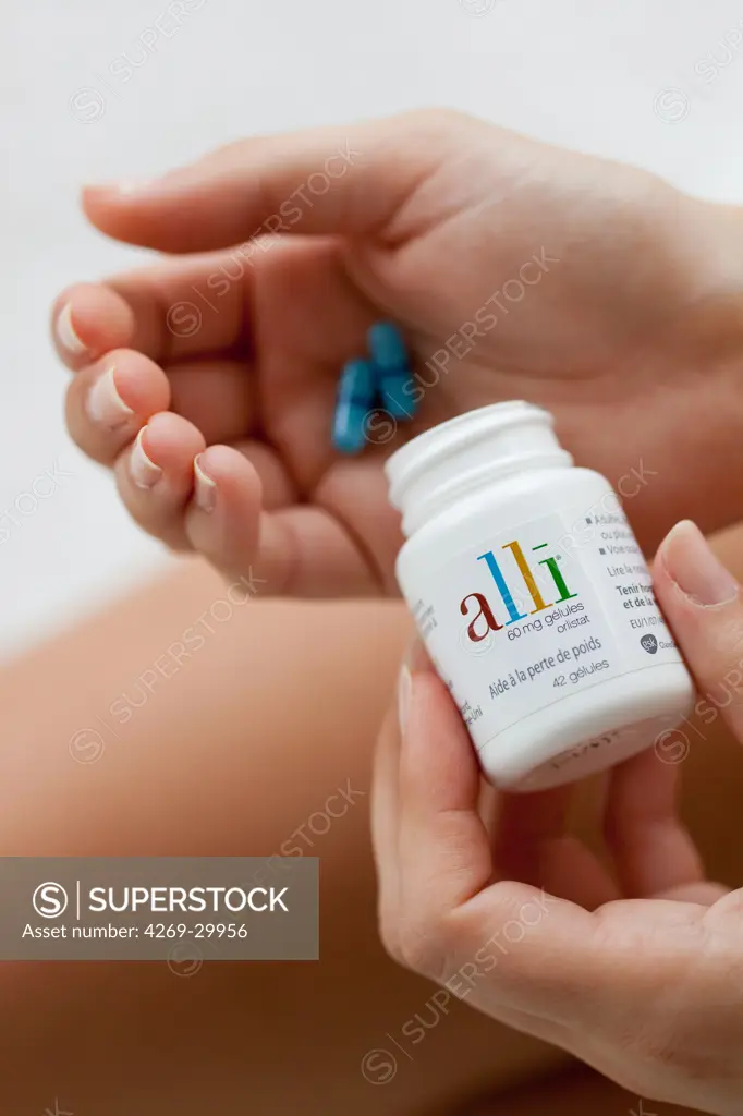 Woman taking Alli medicine. Alli is a half-dose version of the diet drug Xenical (Orlistat) produced by GlaxoSmithKline (GSK). First anti-obesity drug, available in pharmacy without prescription in France from May 6 2009.