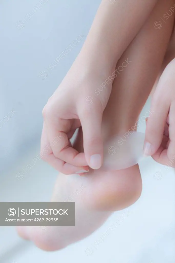 Woman putting a synthetic skin bandage on her heel.