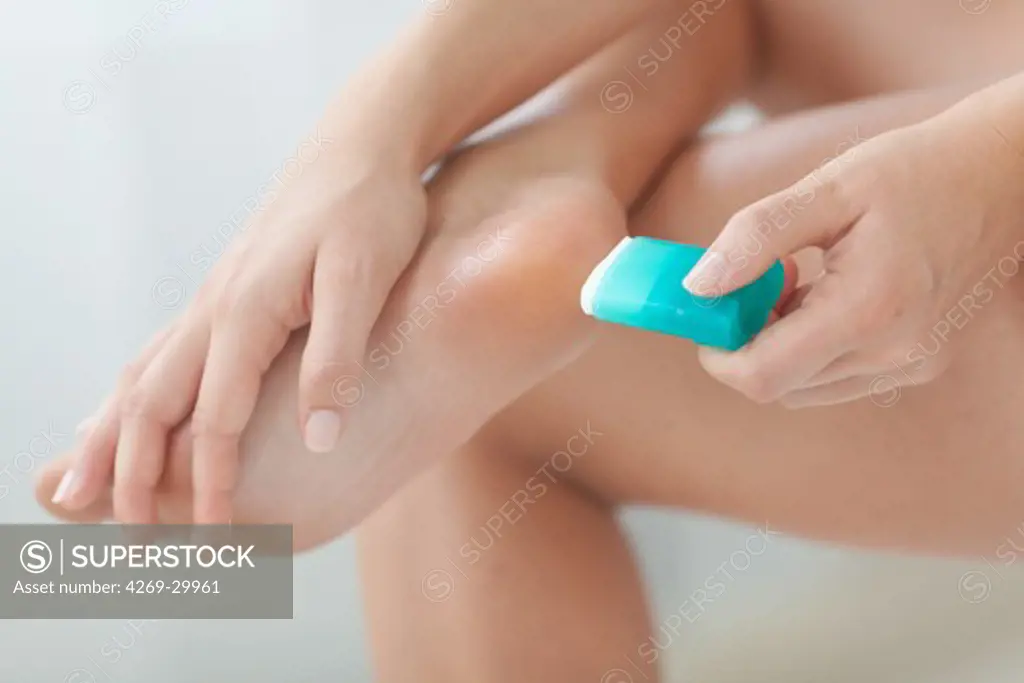 Woman removing hard skin on her foot with a foot file.