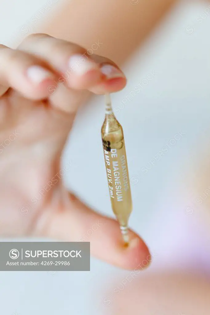Woman holding a glass ampoule of magnesium.