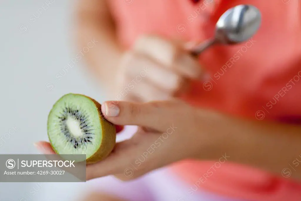 Woman eating kiwi.