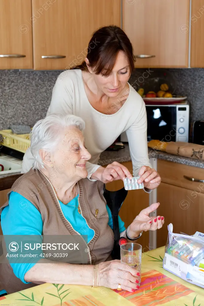 Woman assisting 94 years old woman taking medication.