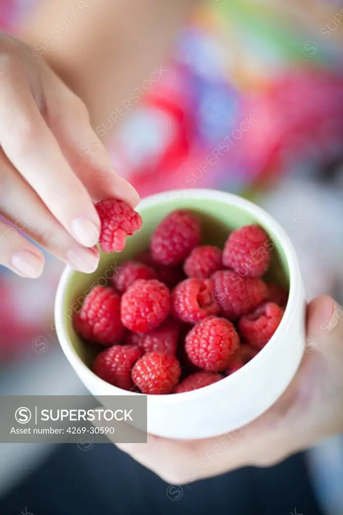 Food. Woman eating raspberries.