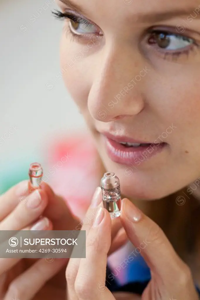 Woman. Woman holding glass ampoule of vitamin D.