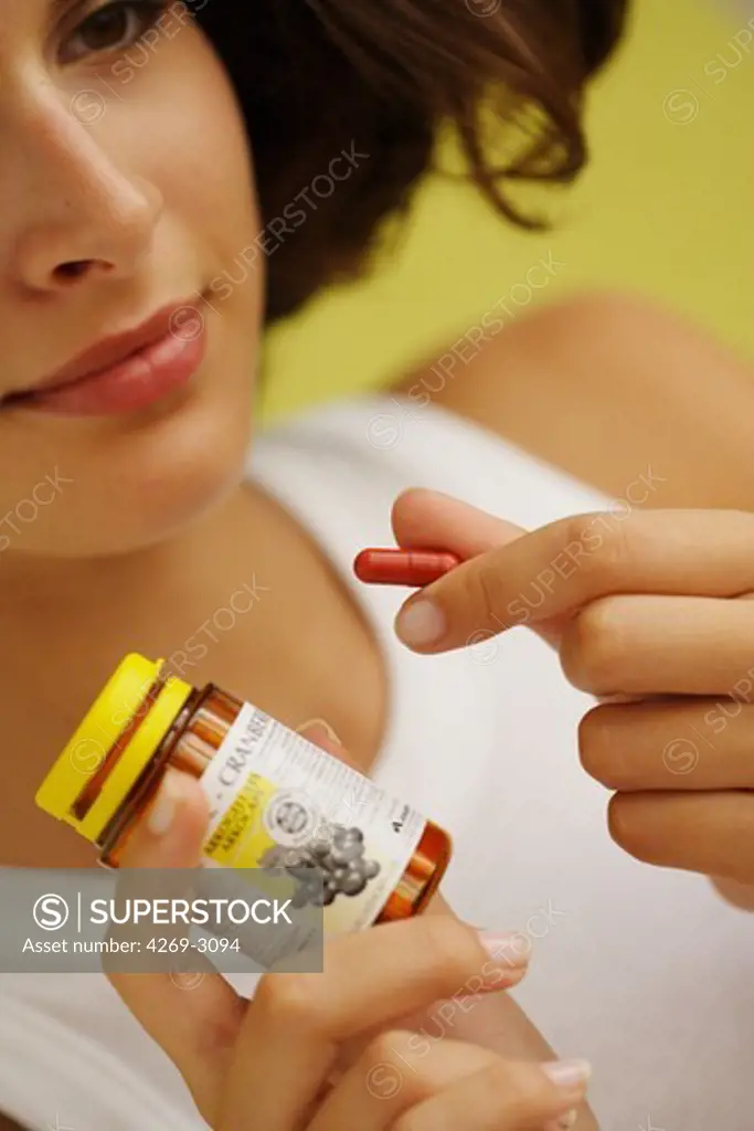 Young woman taking cranberry capsules for cystitis prevention.