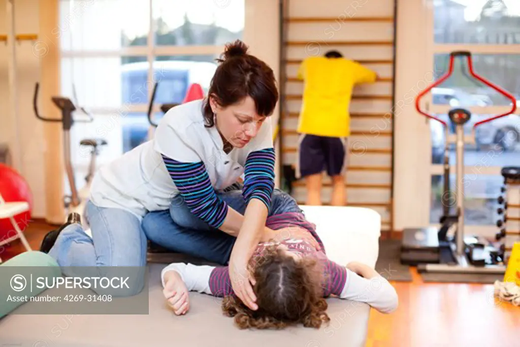 Physical Therapist practicing stretching and flexibility of a 12 year old girl suffering from scoliosis.