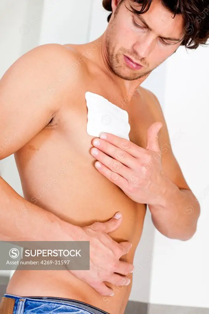 Man applying heat patch for backache.