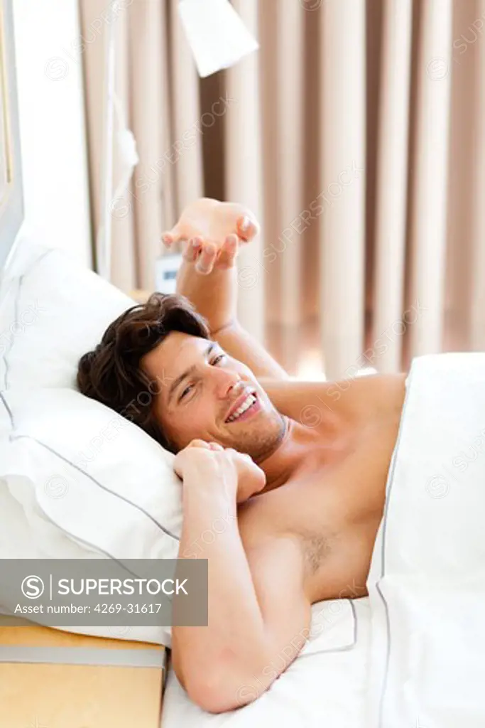 Man waking up and stretching in bed.