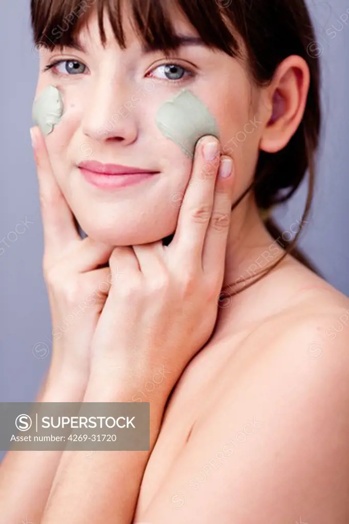 woman applying green clay cosmetic beauty mask.