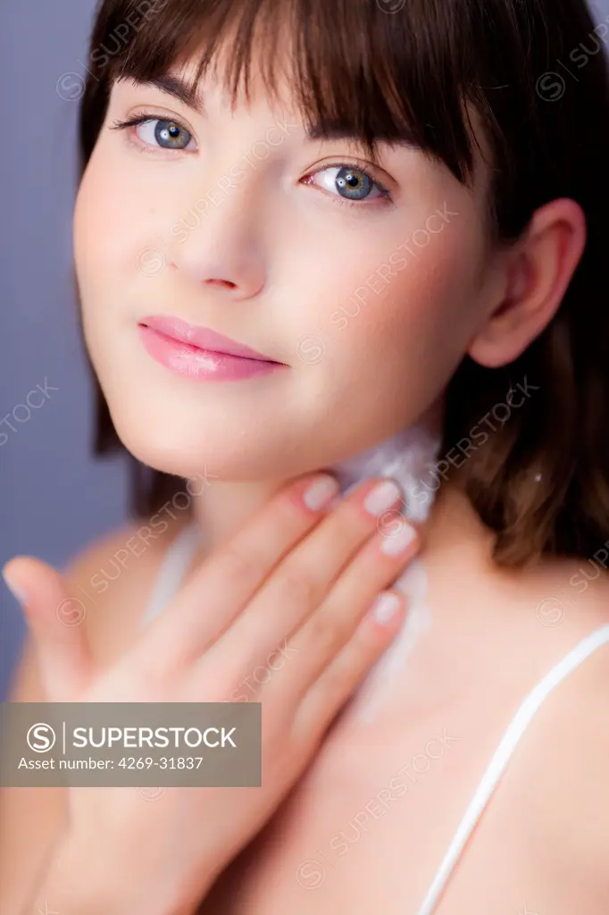 woman applying moisterizing cream on her neck.