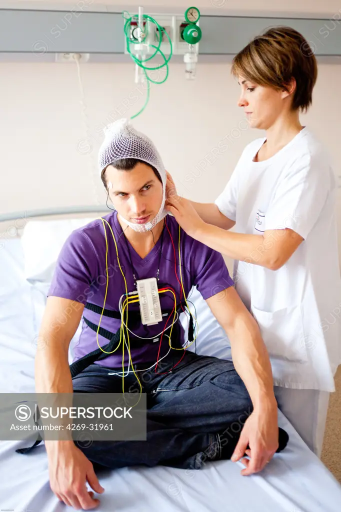 Man undergoing a polysomnographic examination. The polysomnography is the study of the physiological activity of the body during sleep, and includes the measurement of the lungs, heart and brain activity. The interpretation of these recordings can reveal disfunctions like sleep apnea, snoring, hypersomnia, insomnia... Limoges hospital, France.