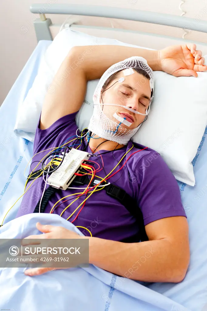 Man undergoing a polysomnographic examination. The polysomnography is the study of the physiological activity of the body during sleep, and includes the measurement of the lungs, heart and brain activity. The interpretation of these recordings can reveal disfunctions like sleep apnea, snoring, hypersomnia, insomnia... Limoges hospital, France.