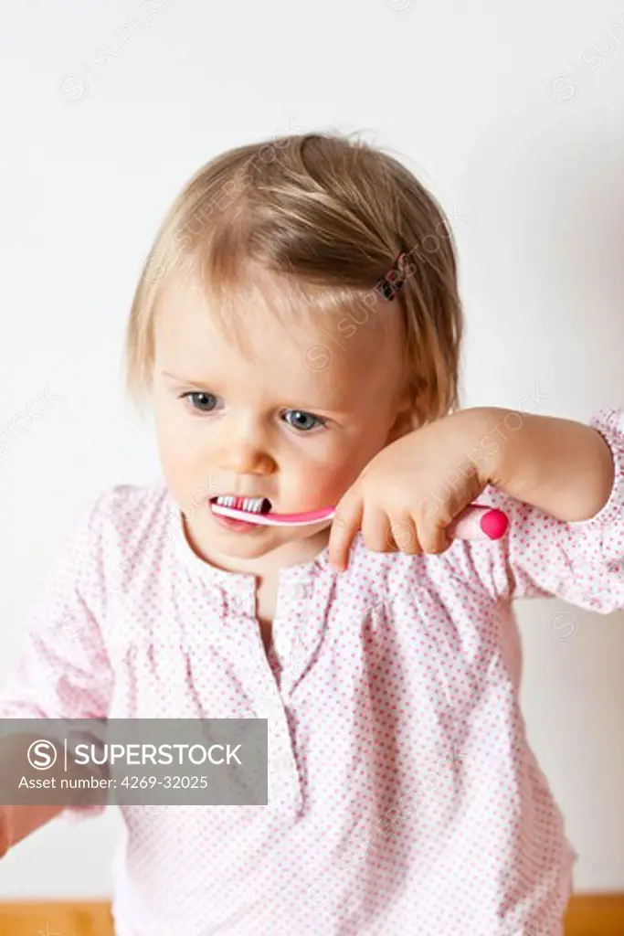 18 month old baby girl brushing her teeth.