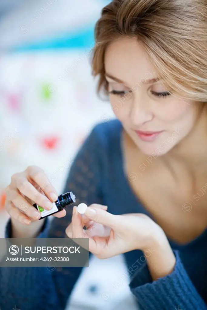 woman applying essential oil on a neutral pill.