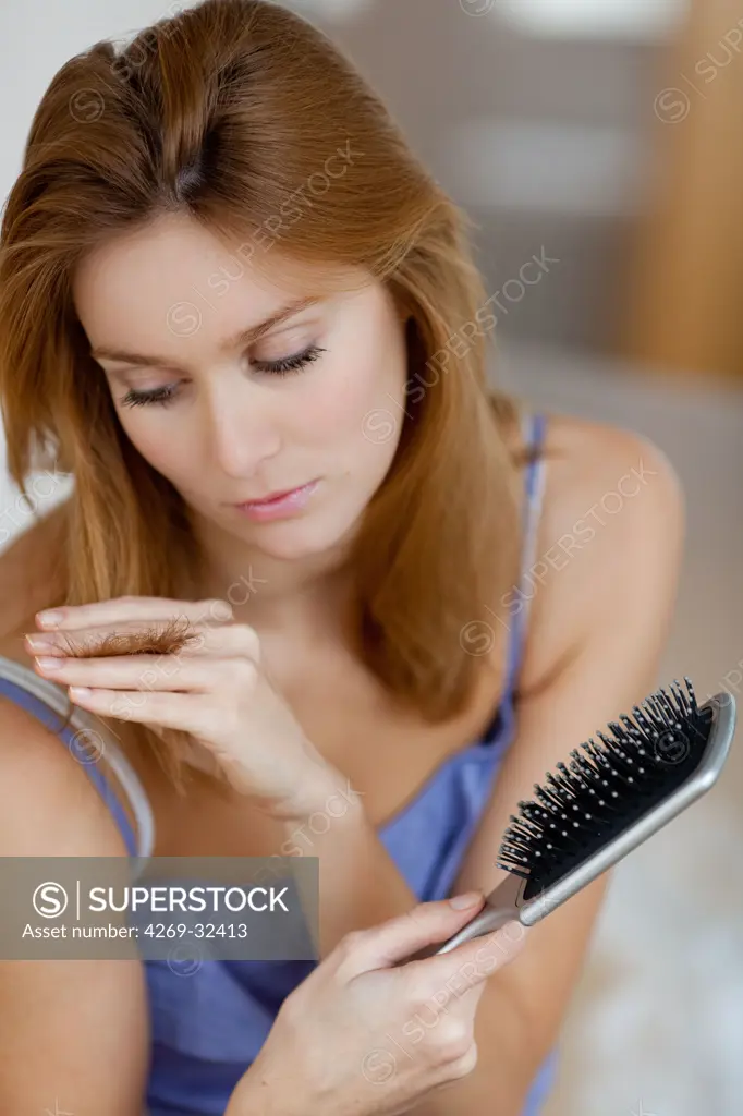 woman inspecting the tip of her hair.