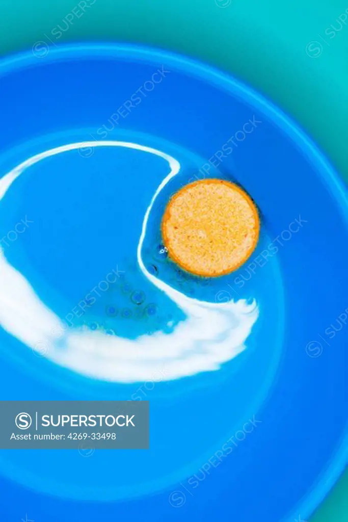 Vitamin C tablet dissolving in a glass of water.