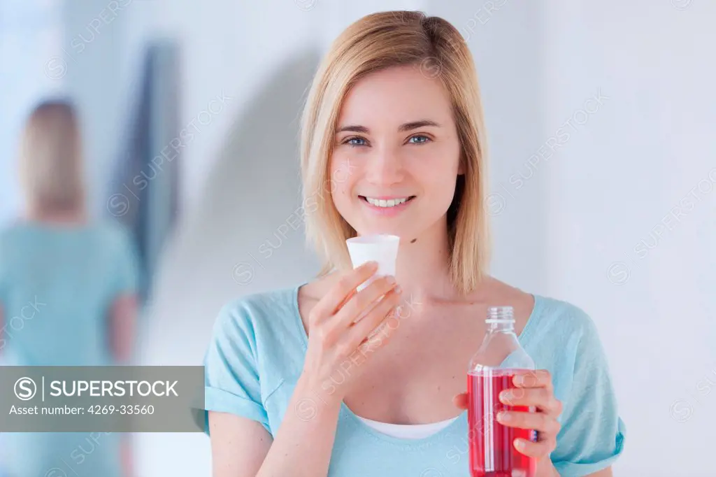 Woman using mouthwash.