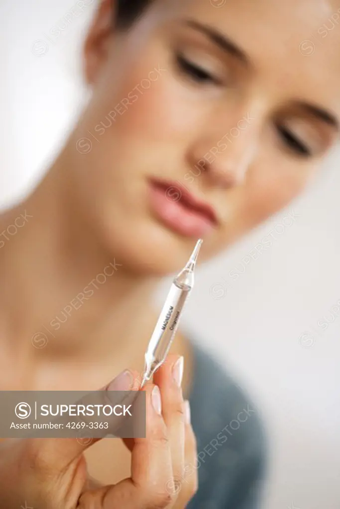 Woman taking a glass ampoule of trace elements (magnesium).