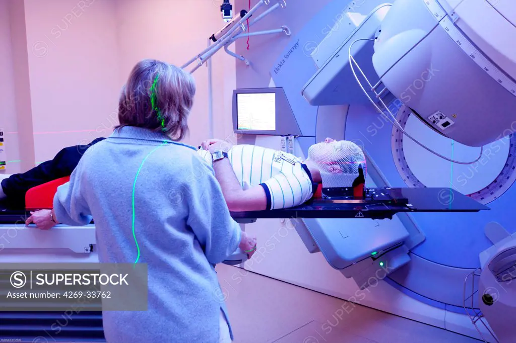 Radiotherapy radiographer with a male patient treated for a brain cancer with radiotherapy. Latest generation particle accelerator. Radiotherapy center pole of Oncology Hospital of Bordeaux. Radiotherapy center pole of Oncology Hospital of Bordeaux. Hospital Haut-Leveque.