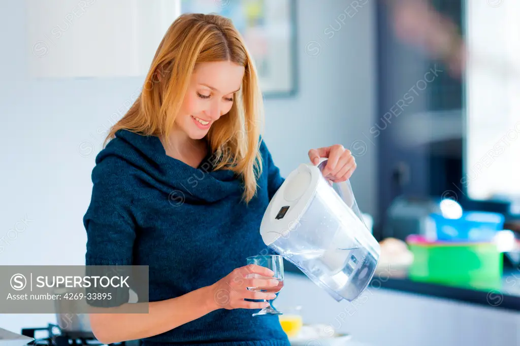 Woman pouring water with filtering pitcher.