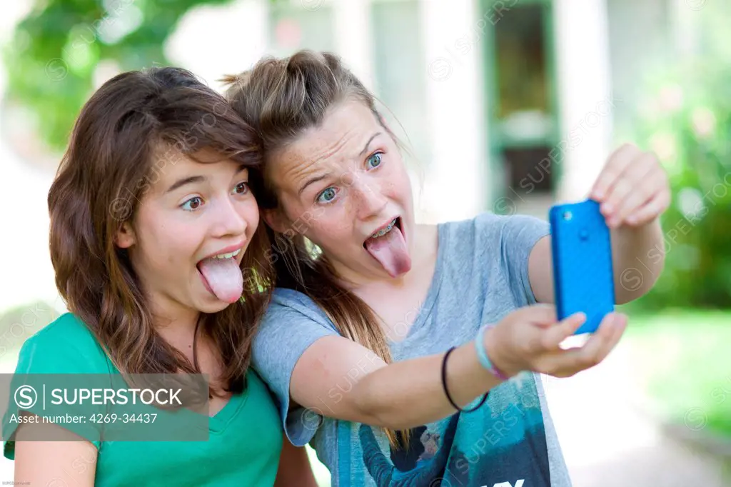 Teenage girls photographing themselves with a mobile phone.