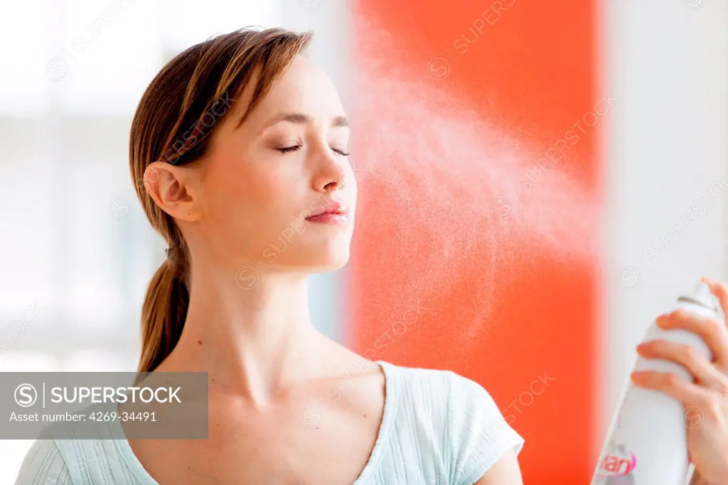 Woman spraying water on her face.