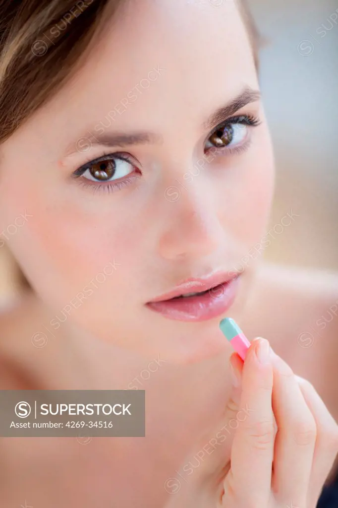 Woman taking gelatine capsule medication.
