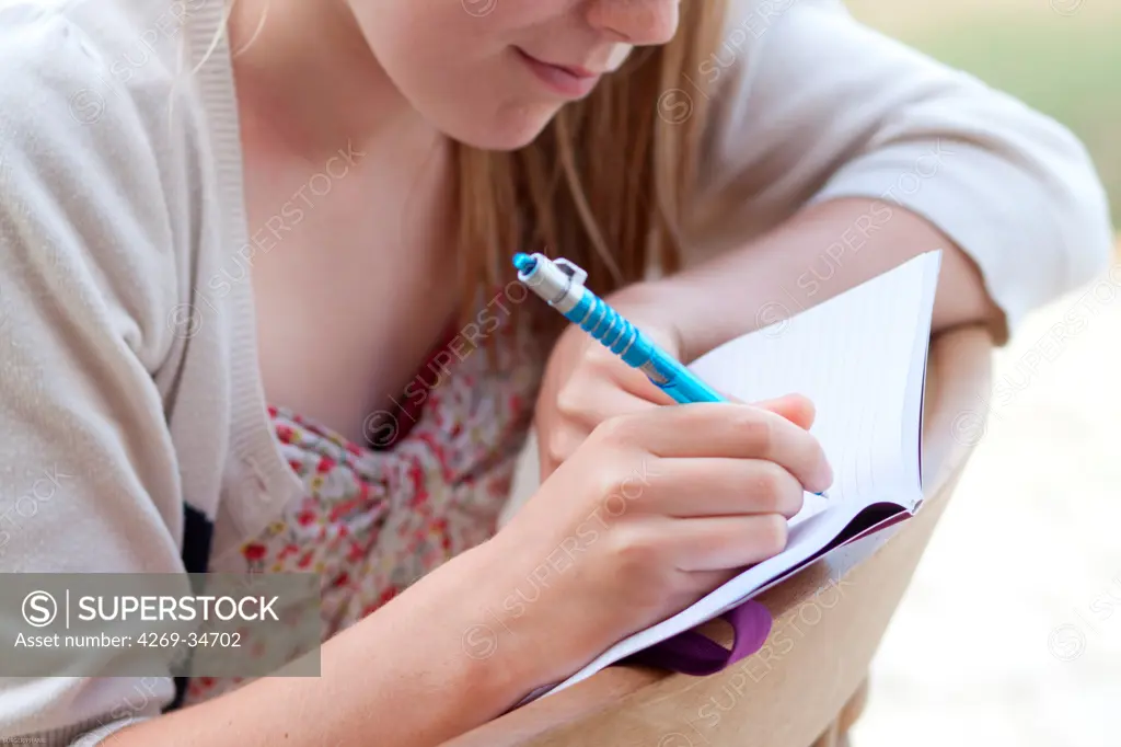 Teenage girl writing on her diary.