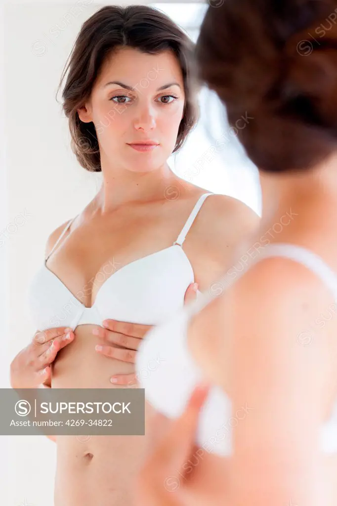 Woman watching her breasts in a mirror.