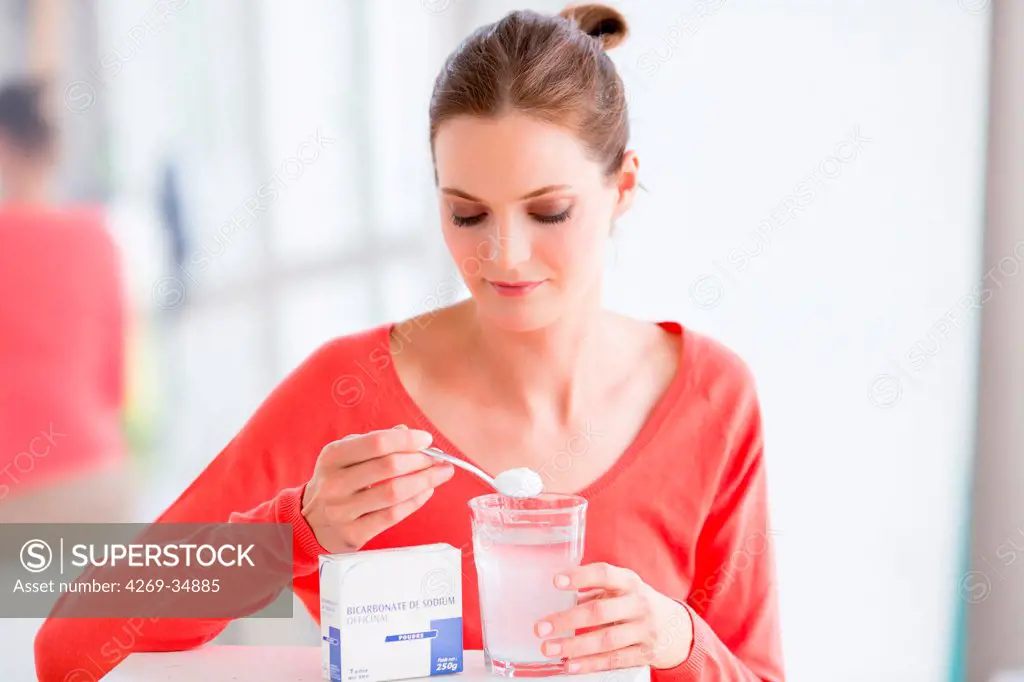 Woman taking powder of sodium bicarbonate or baking soda.