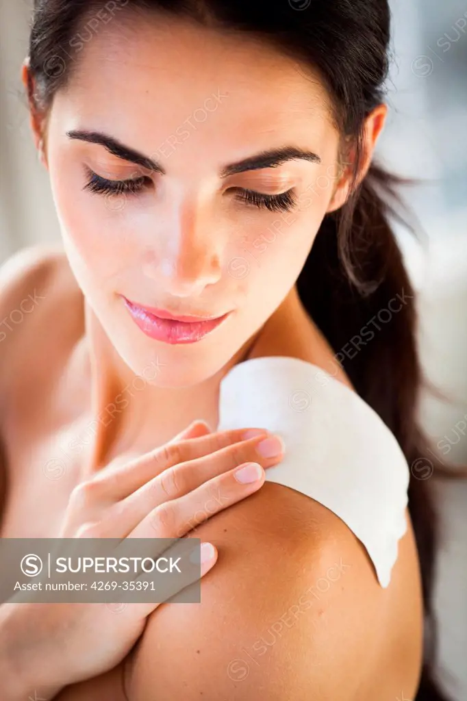 Woman applying heat patch for backache