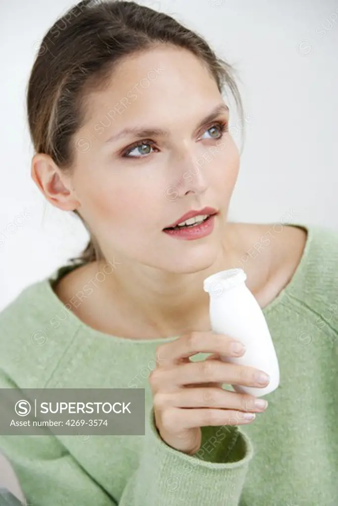 Woman taking functional food or pharmafood : normal food enriched with certain substances (vitamins, trace elements, etc.). In addition to its nutritional functions, this dairy product would boost the natural defenses of the organism.