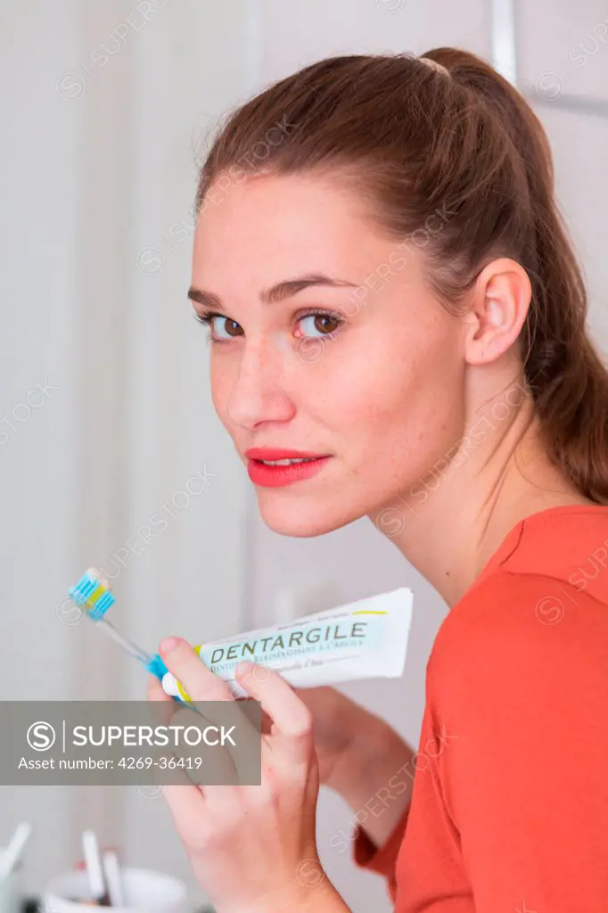 Woman brushing her teeth with green clay toothpaste