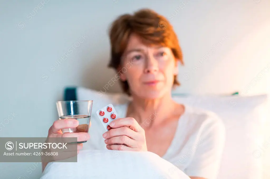 Restless woman taking tablets in bed unable to sleep