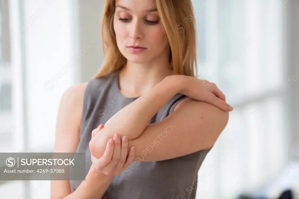 Woman, Woman suffering from a pain in the elbow (tennis elbow).