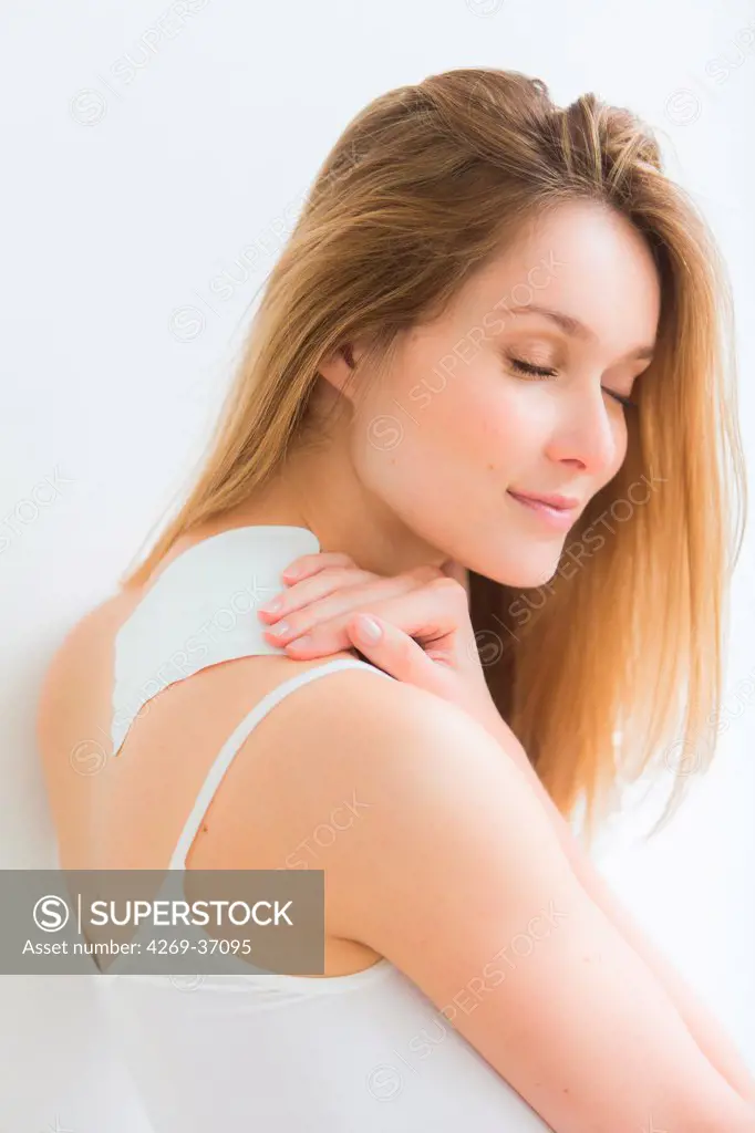 Woman, Woman applying heat patch for backache.