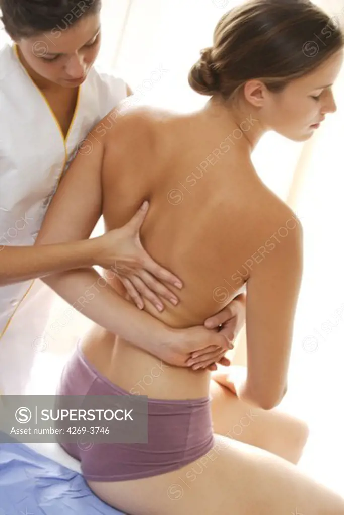 Back of a woman being manipulated by osteopath. Osteopathy uses massage and manipulation to treat a range of disorders, based on an understanding of the musculoskeletal system.