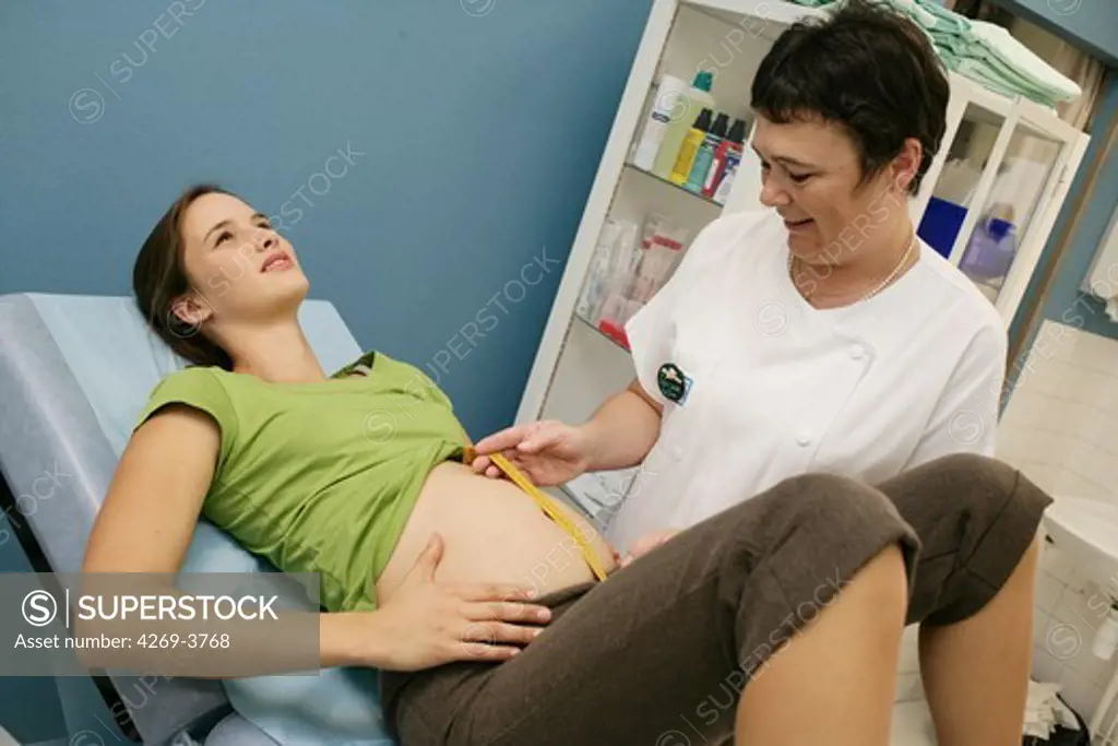 Maternity Department, Angoulème hospital, France. 3 months pregnant woman at antenatal consultation. Midwife measuring the fundal height to determine the development of the fetus.