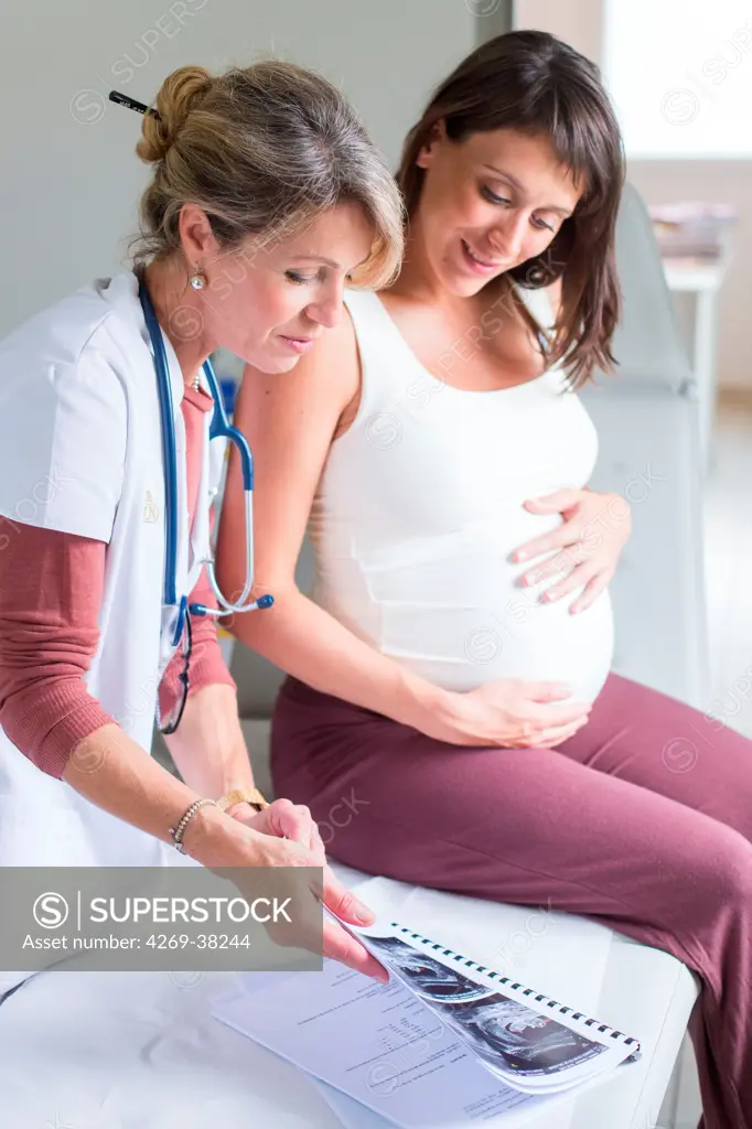 Gynecologist commenting foetal ultrasound scans of a pregnant woman.
